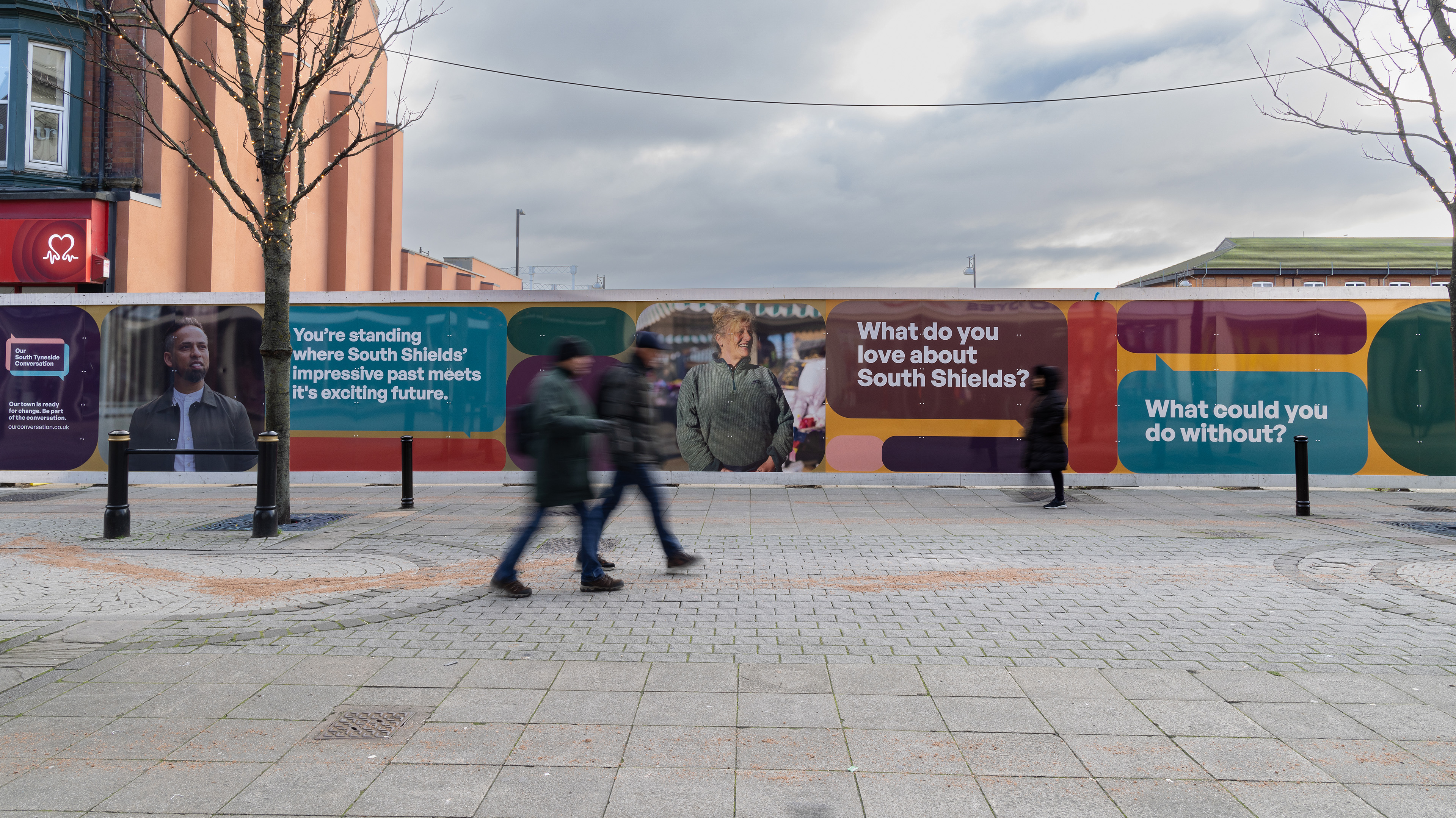 People walking in street with advertising hoardings in the background.