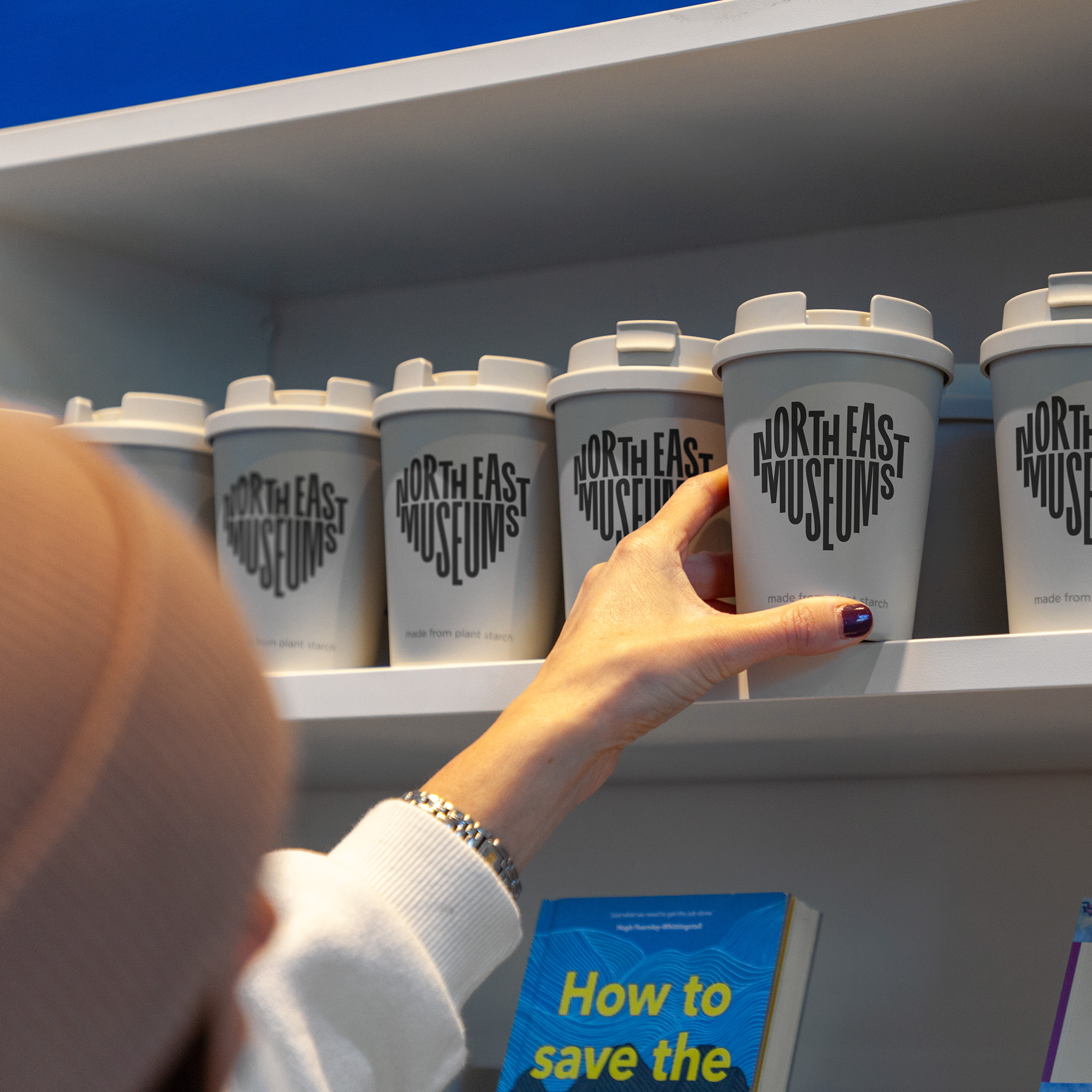 Person reaching for cup that reads North East Museums