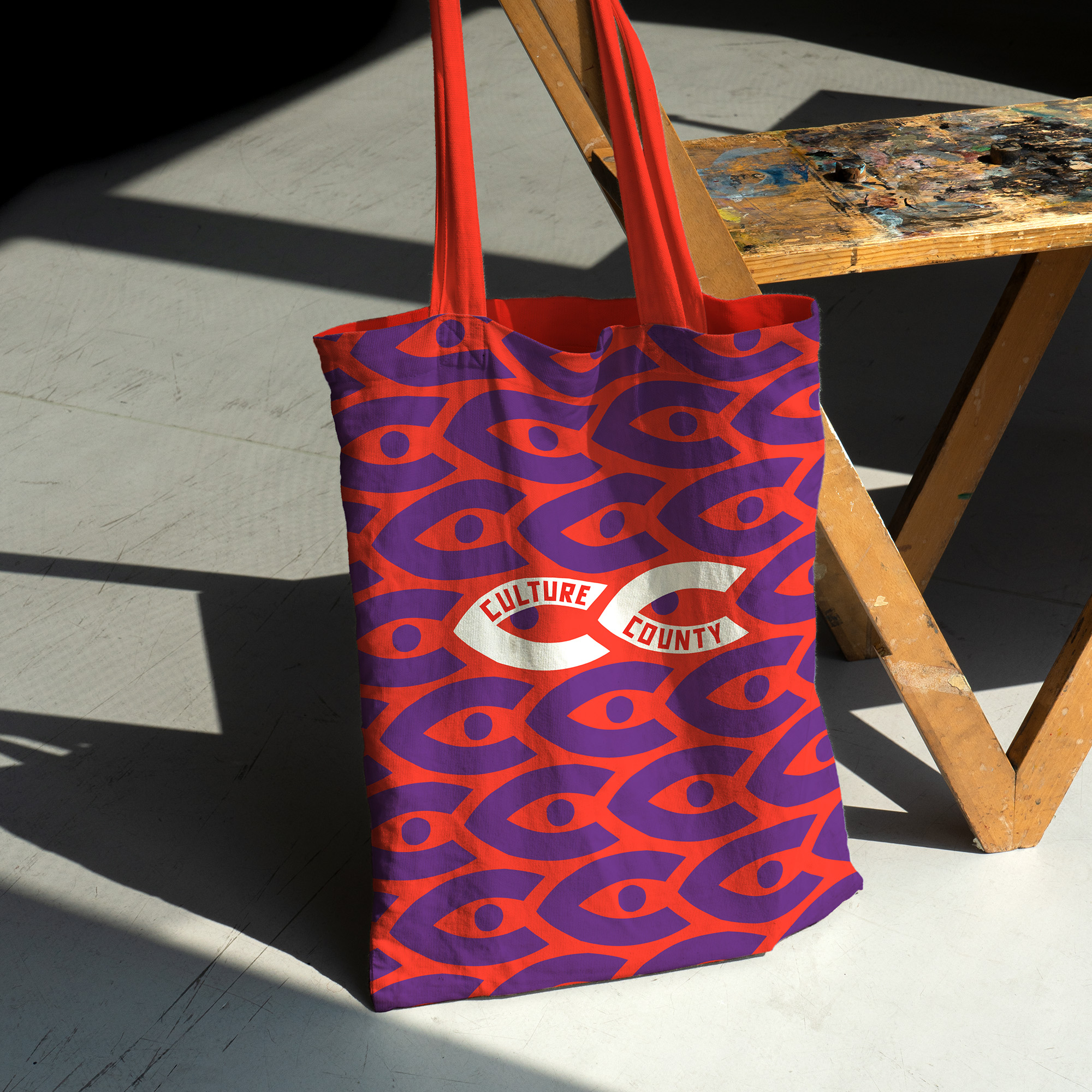 Colourful tote bag set against wooden ladder.