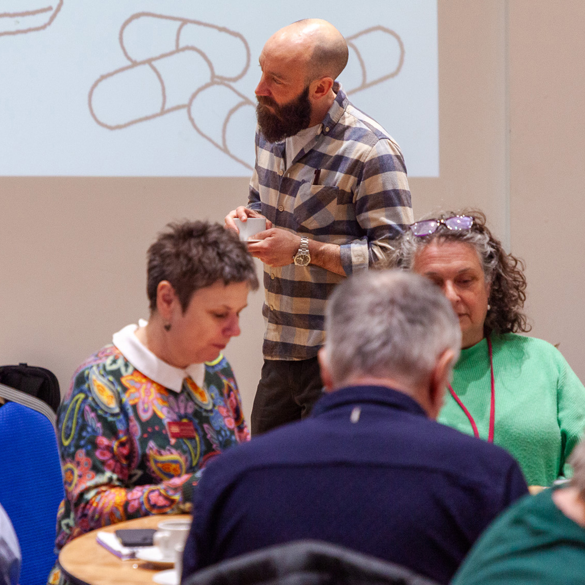 People working together and chatting in a group as a Director watches on.