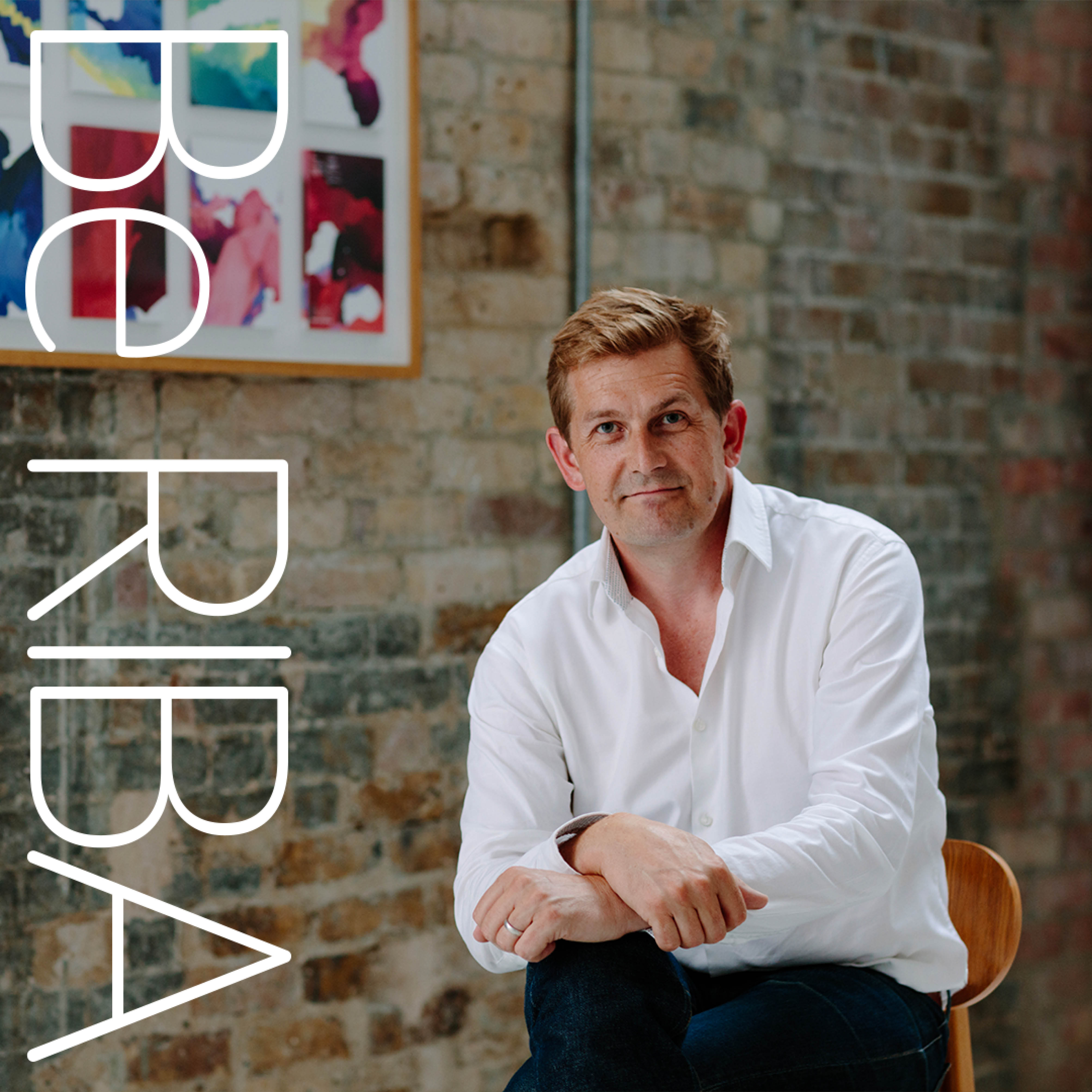 A man in a shirt against a brick wall