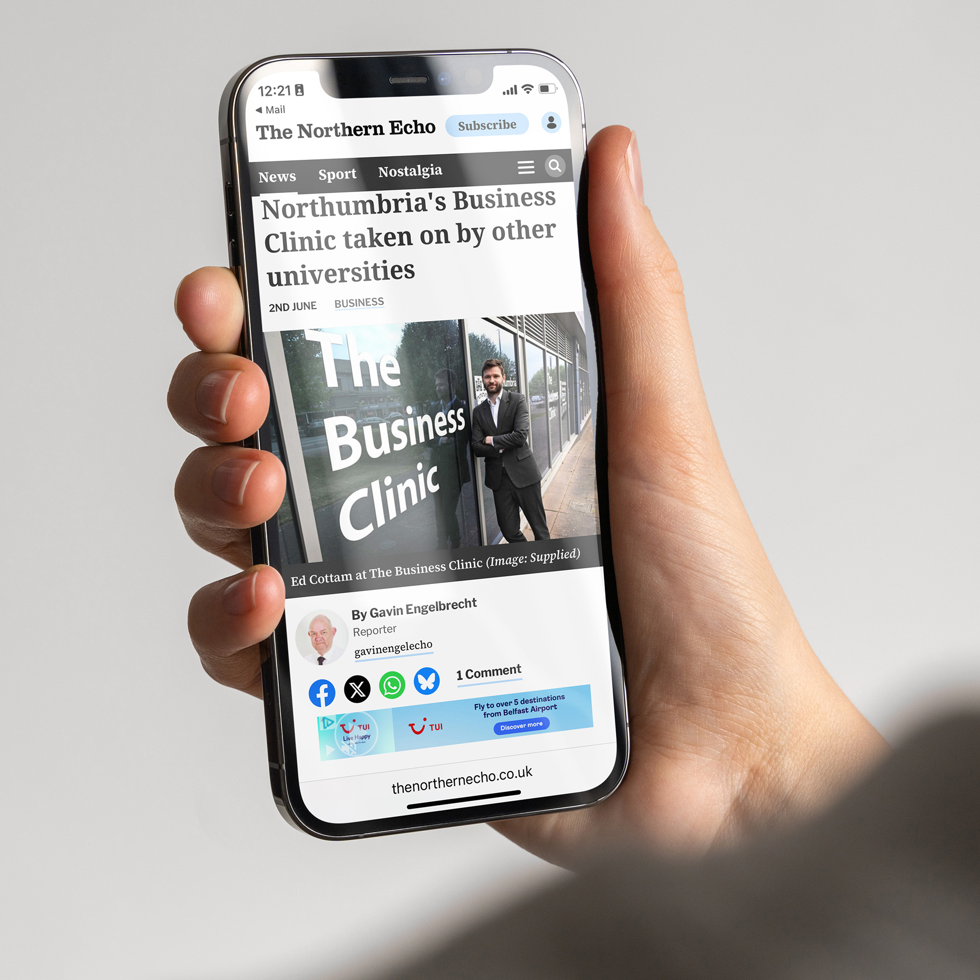 A hand holding a phone with a news article on screen.