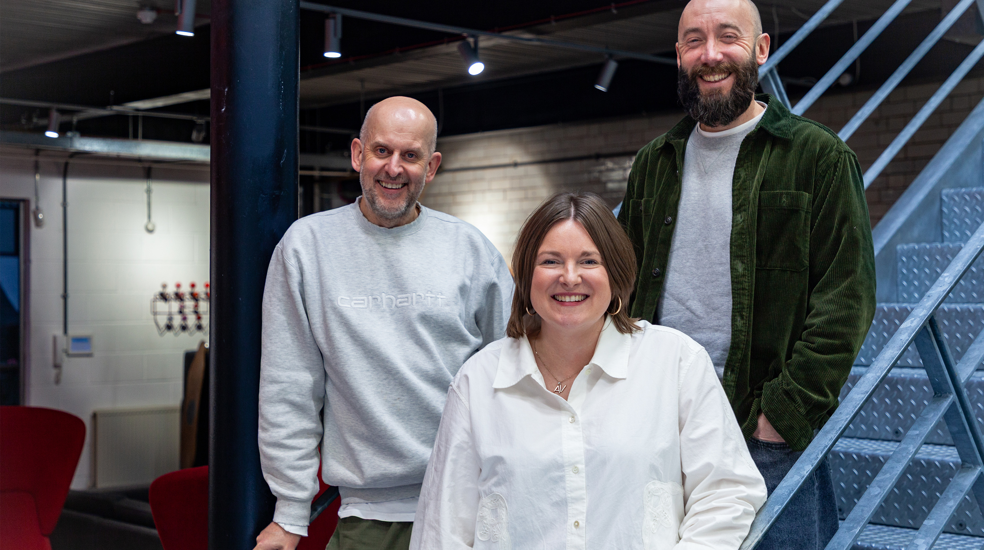 Three people standing on a staircase in an office.