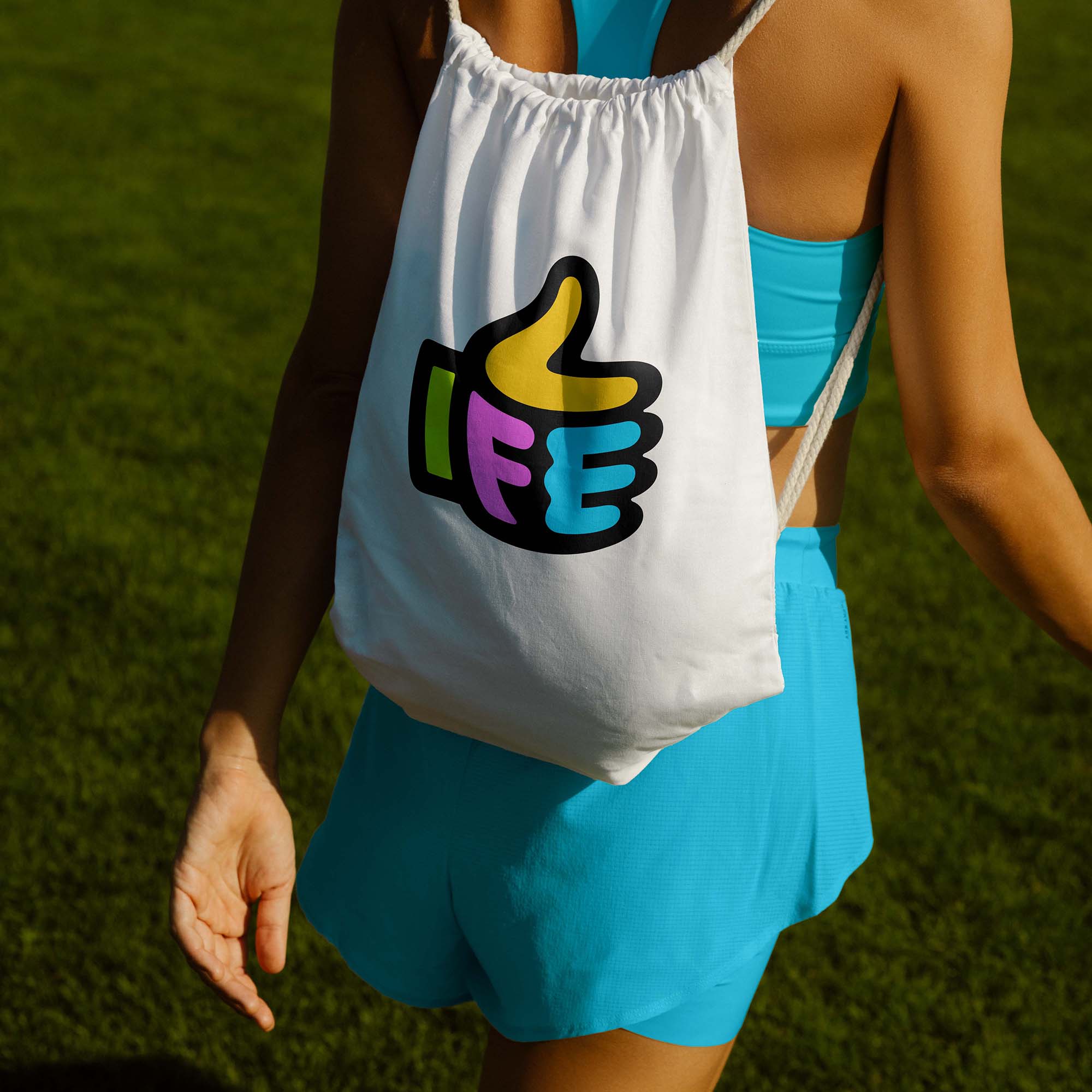 woman walking in gym wear with a backpack on. The backpack has the Life Factory logo on which is a thumbs up emoji