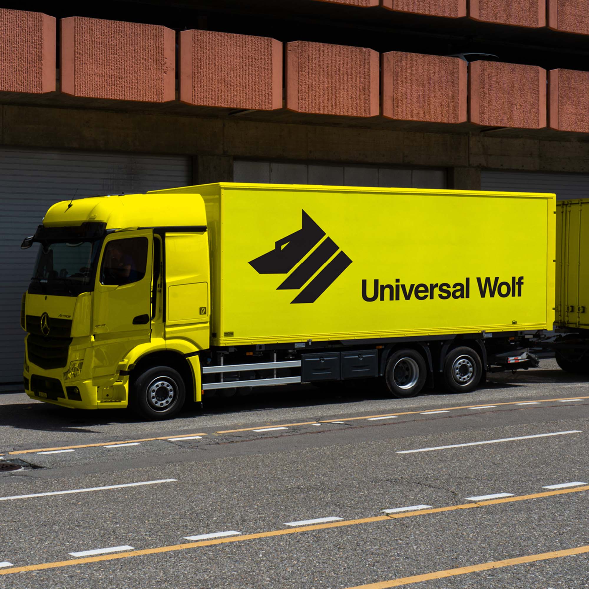 Universal Wolf branded truck on street. The truck is bright yellow with a black logo on the side.