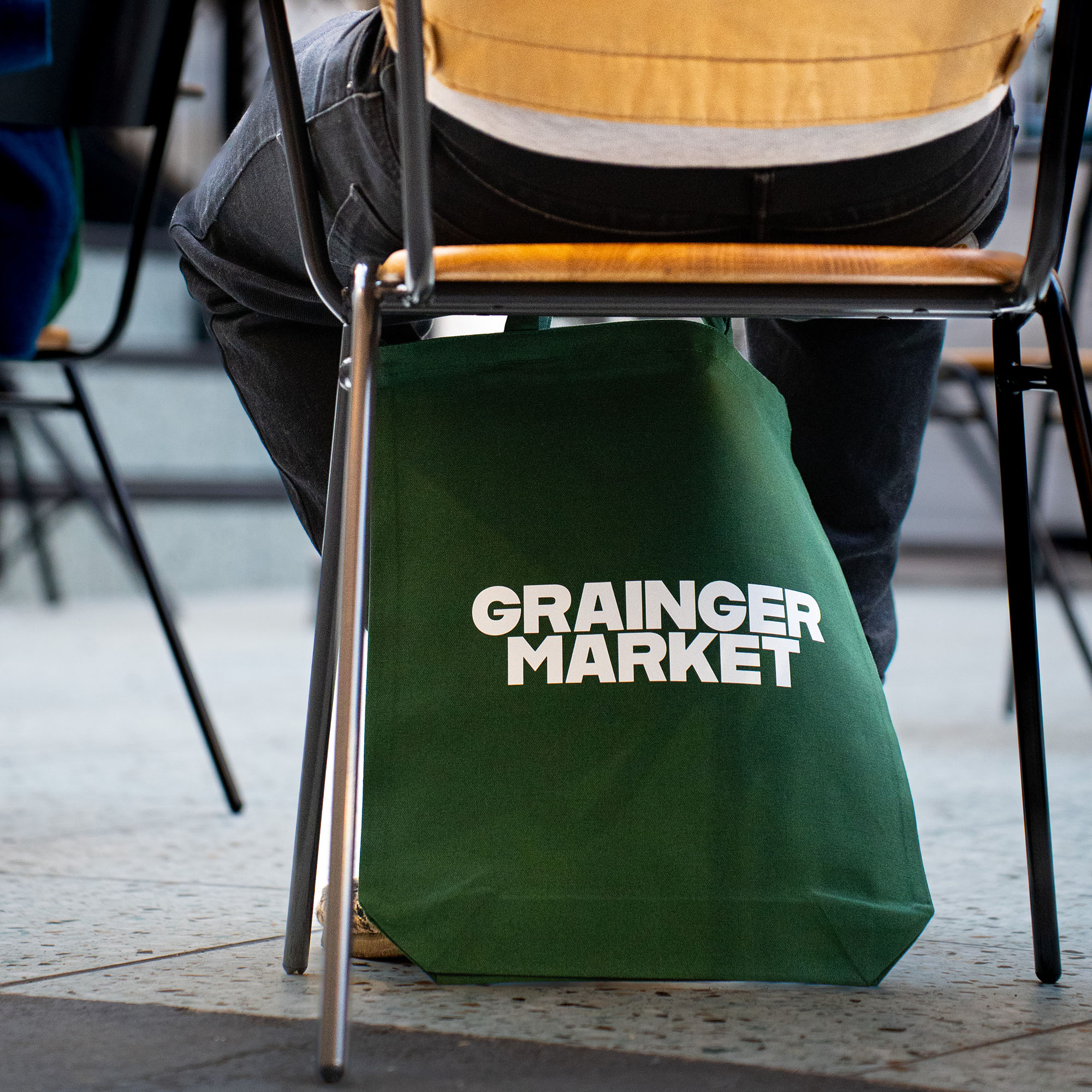 Green tote bag under chair in Grainger Market arcade.