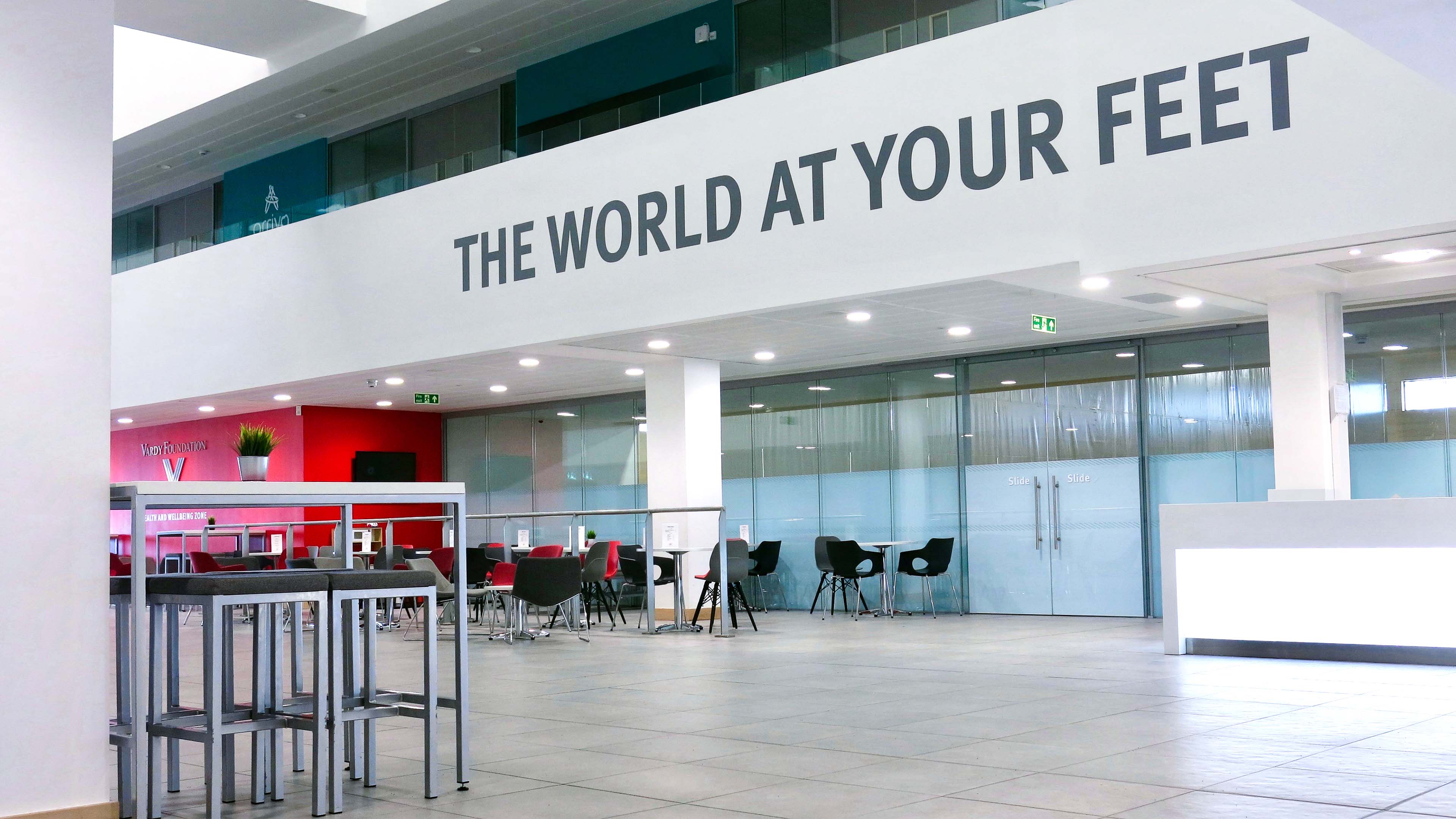 Modern white spacious reception area with the large scale message 'The World at your feet' across the balcony wall.
