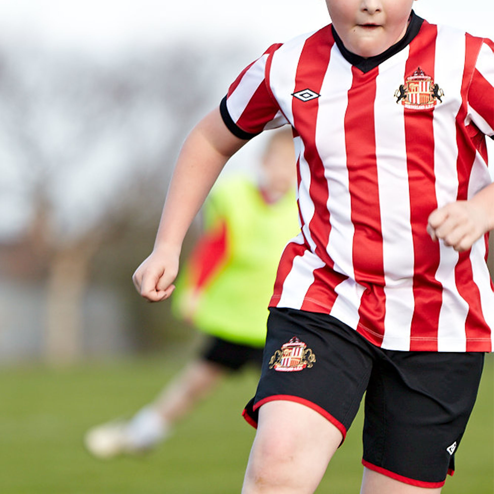 Children actively playing football outside wearing the club strip.