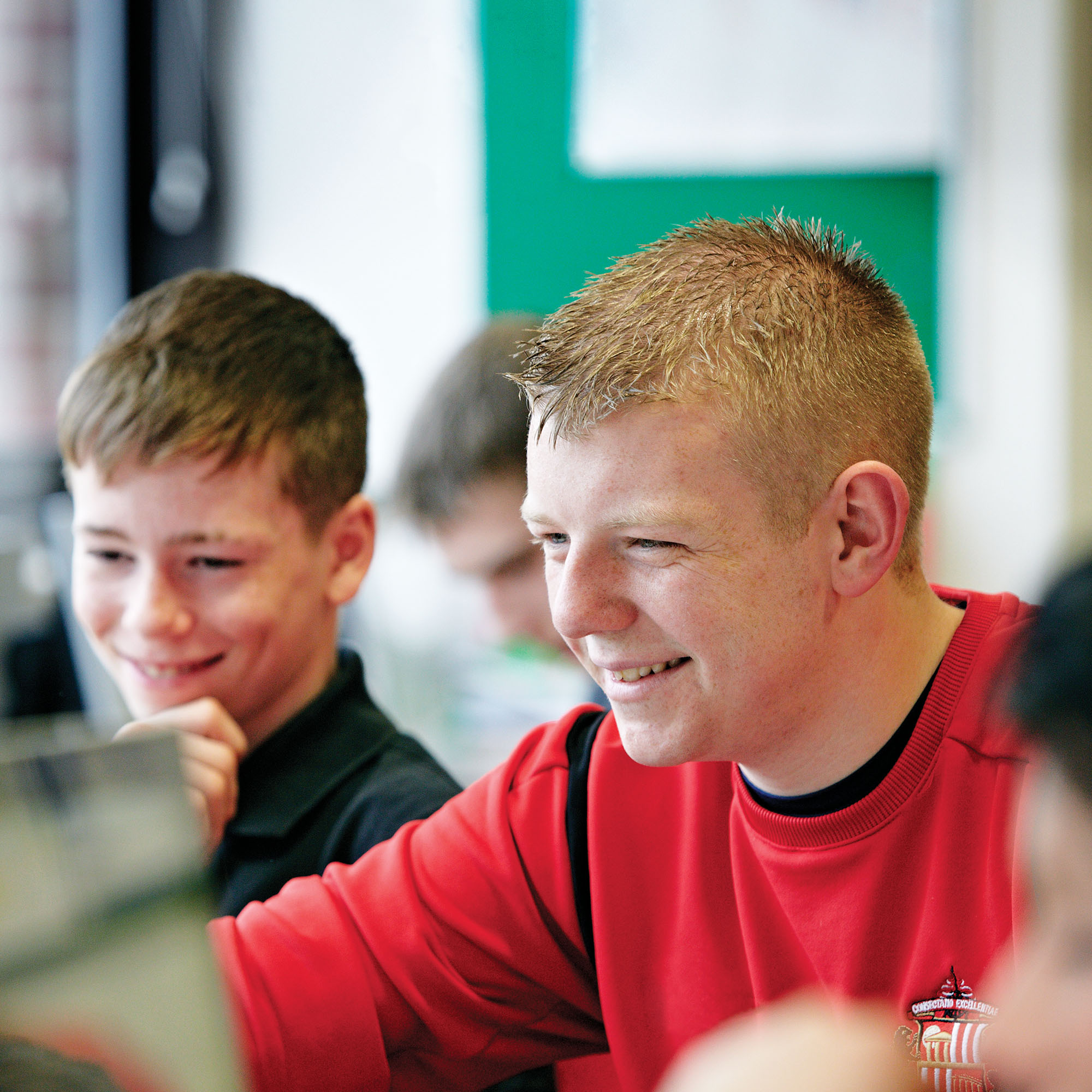 Children sat round a computer in the classroom with Foundation of Light coach.