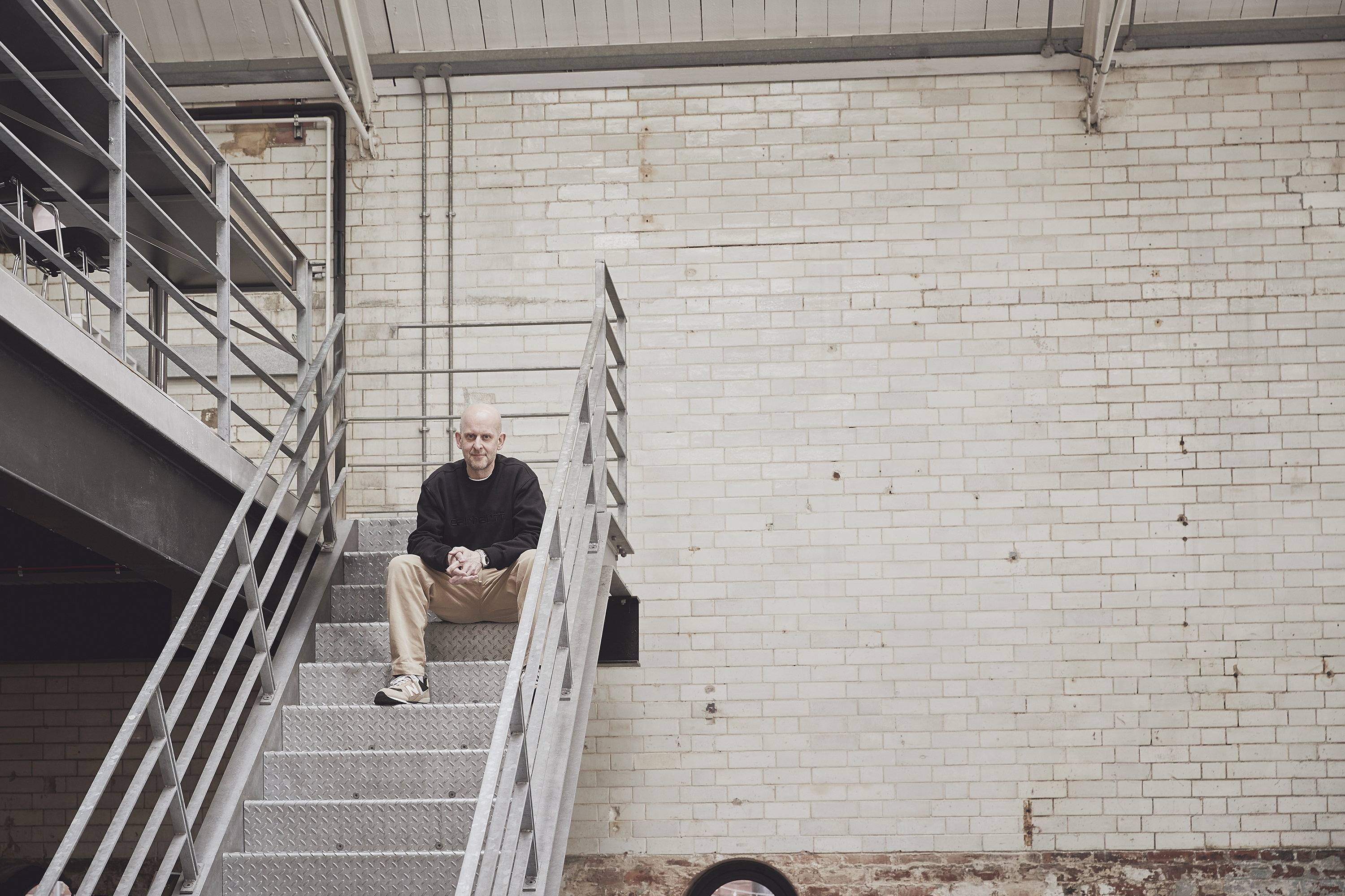 A man sitting on the stairs against a brick wall