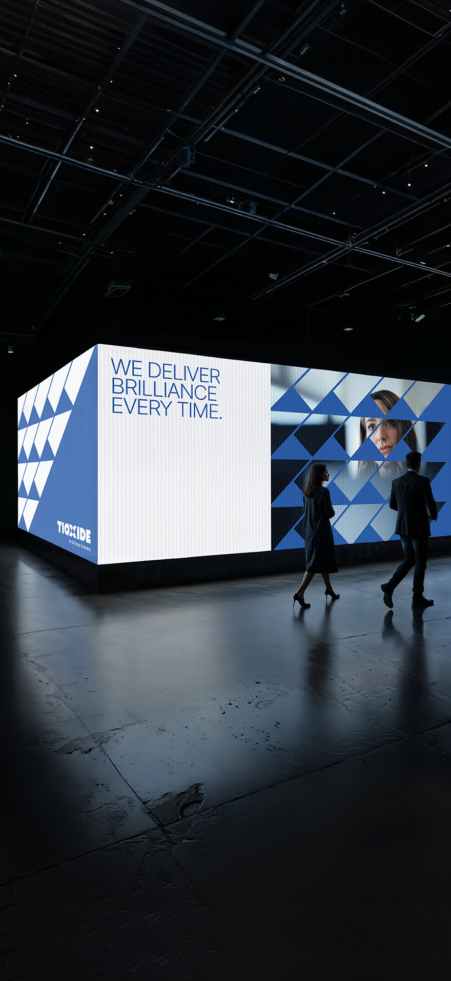 Tioxide identity applied to a large light box in a dark exhibition space environment with people walking in front.