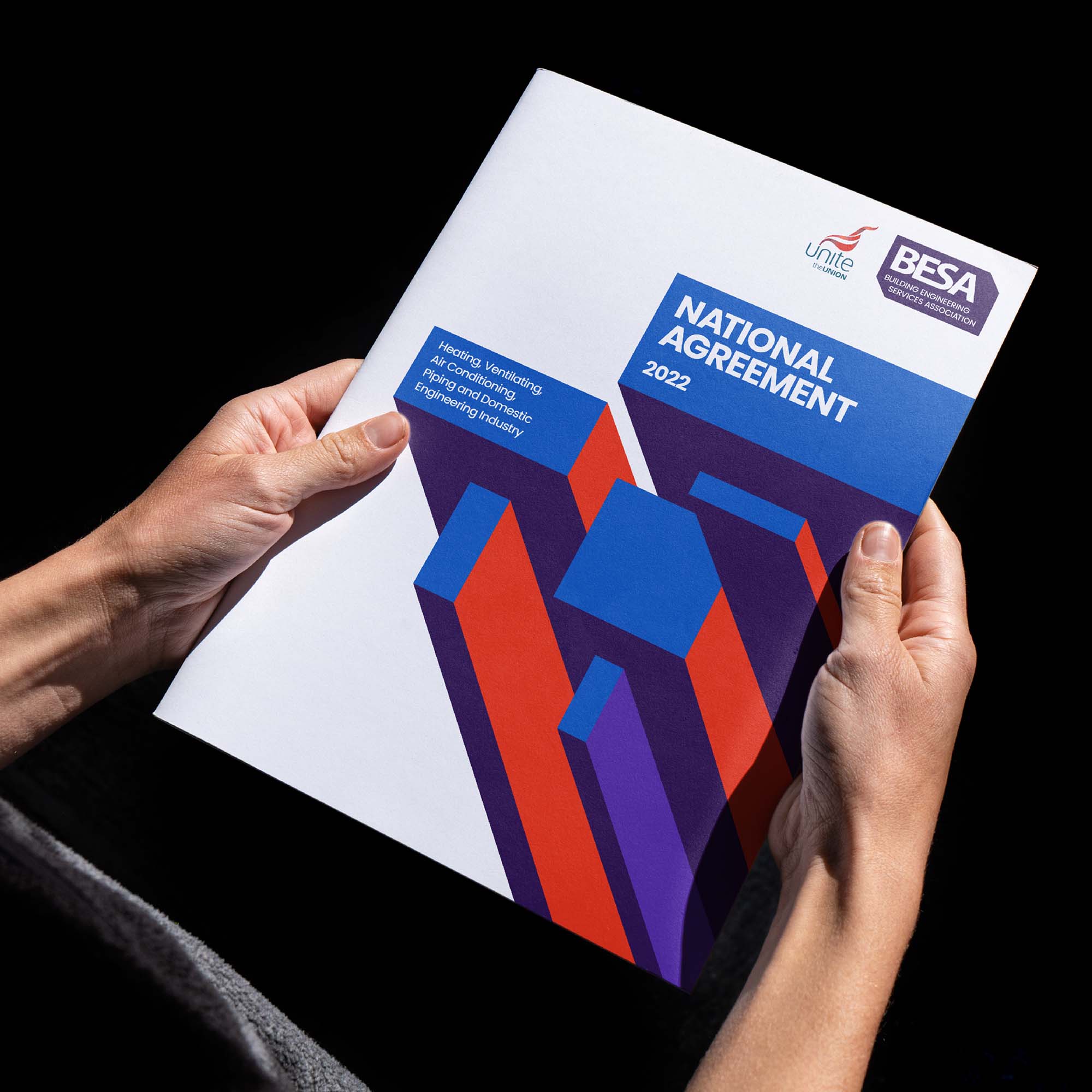 New BESA brochure design held by a young man against a black background