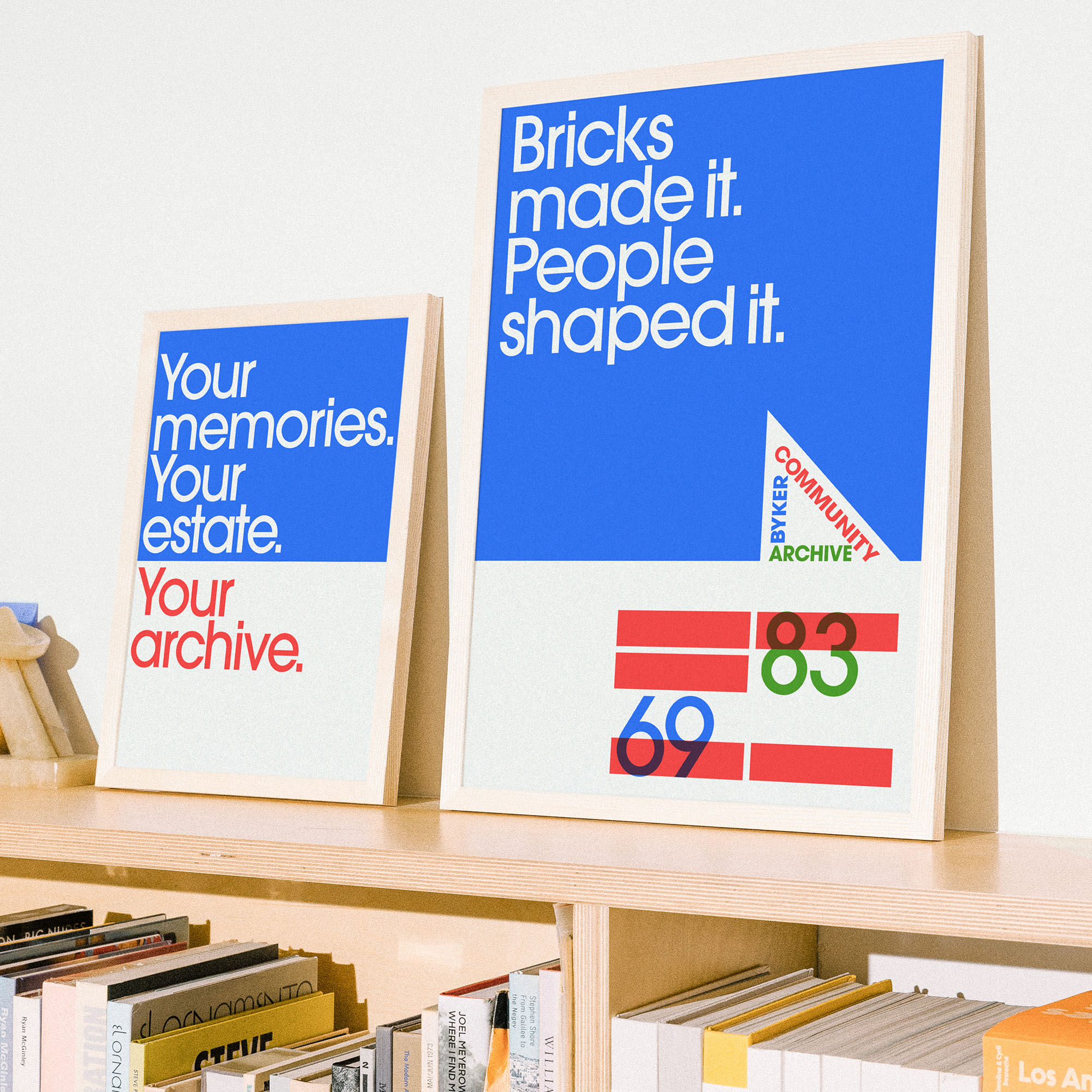 Byker Community Archive posters in wooden frames resting on a modern bookshelf.