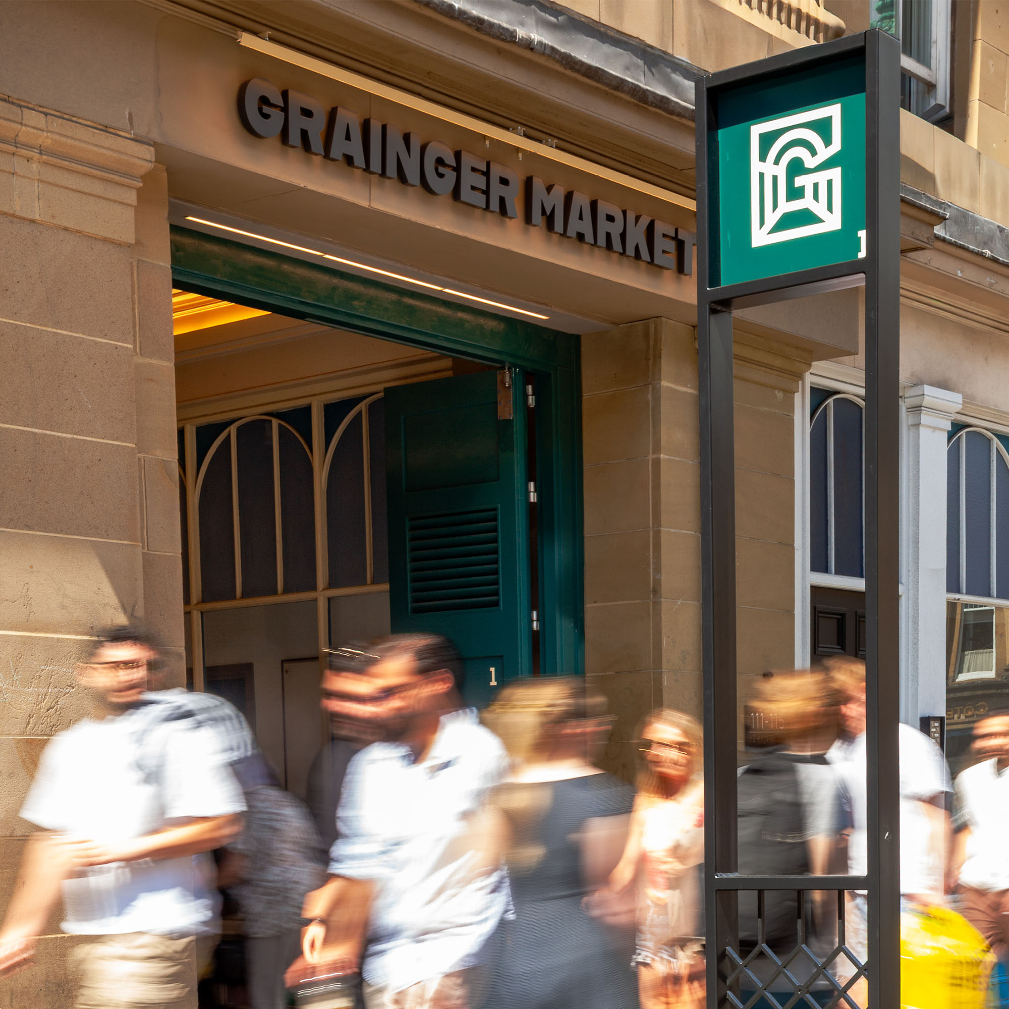 Busy street scene outside Grainger Market Entrance showing the new signage and branding